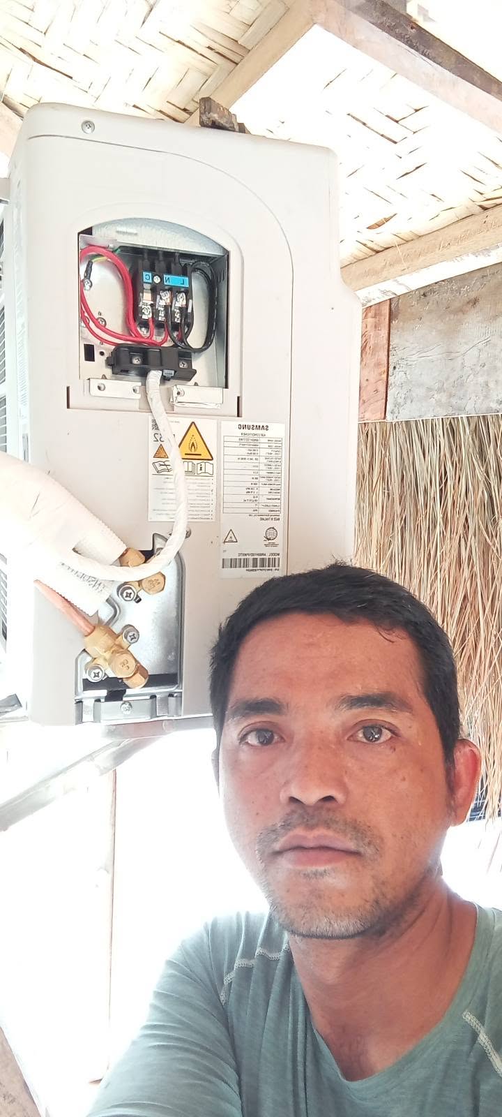 A completed split-type air conditioner installation under a nipa roof