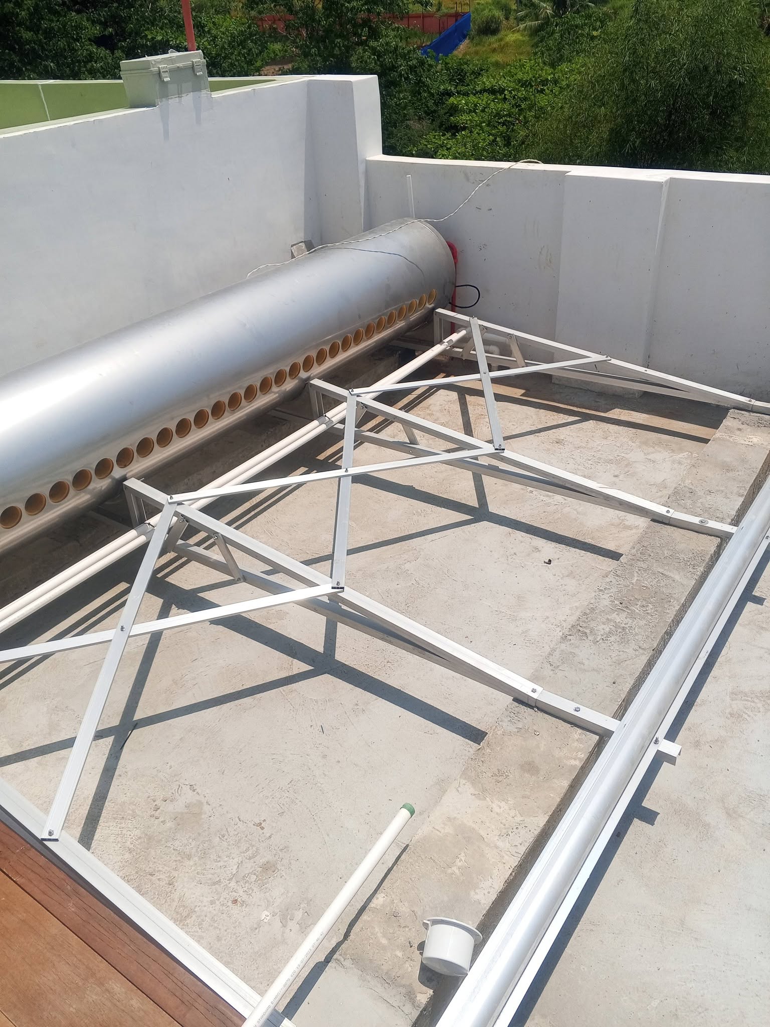 Solar water heater and mounting frames laid out on a concrete roof deck